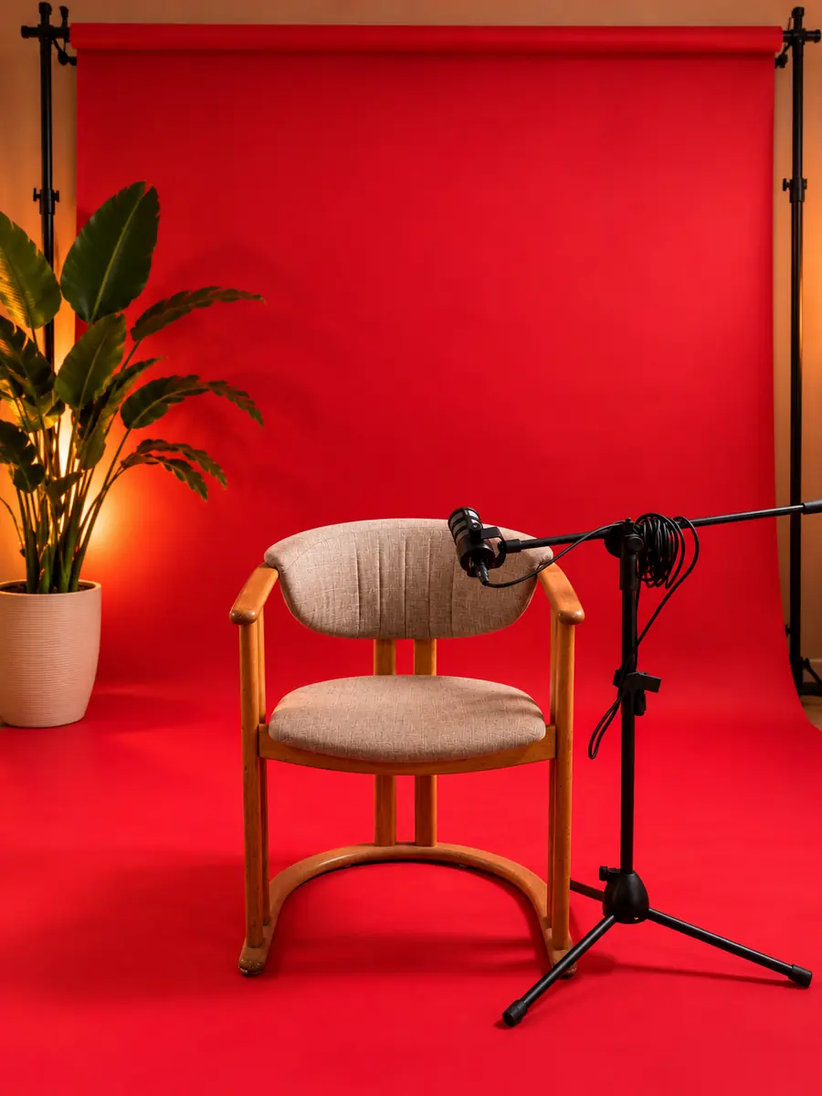 Fauteuil en bois et micro sur pied devant un fond de studio rouge
