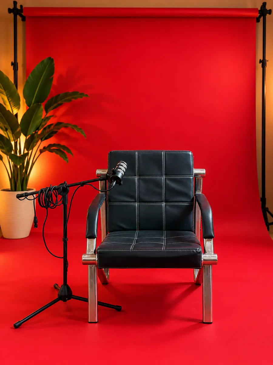 Fauteuil en cuir noir et micro sur fond de studio rouge